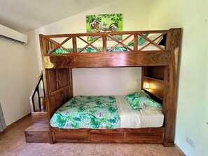 A bunk bed with a wooden frame and a tropical-themed bedspread.
