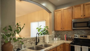 A kitchen with granite countertops, wooden cabinets, a stainless steel sink, a microwave, and an oven.