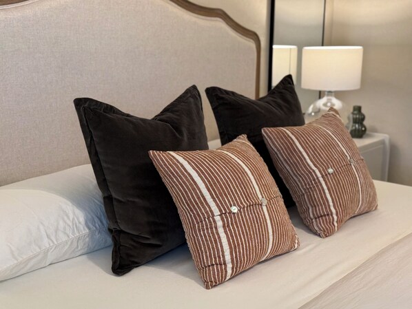 A bed with black and striped pillows, a white pillow, and a nightstand with a lamp. - Serene 3-bedroom house 15 min. from downtown Phoenix and Sky Harbor Airport. (Phoenix)