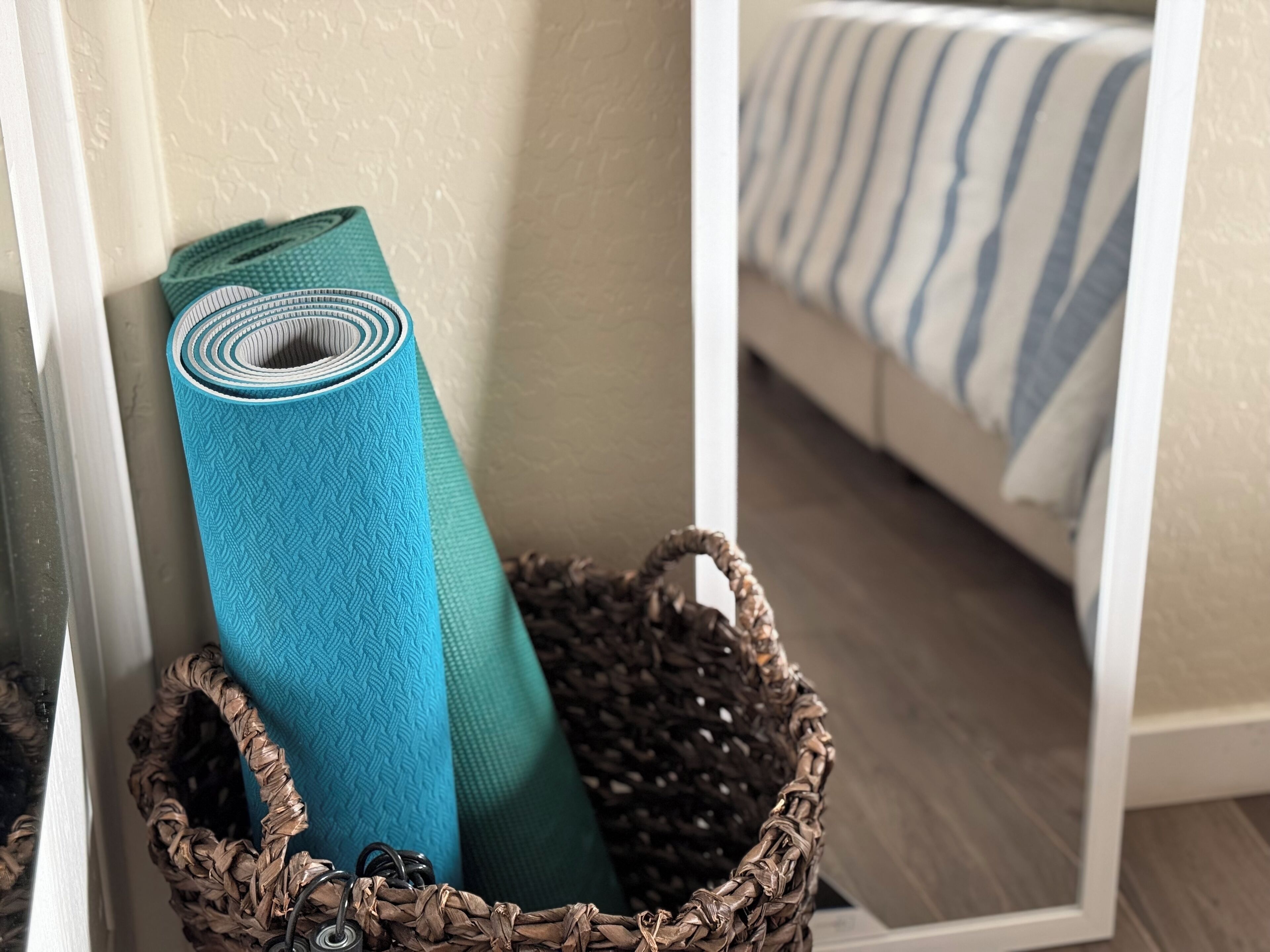 Una cesta tejida con una esterilla de yoga enrollada y una bolsa tejida.