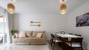 Una sala de estar con sofá, mesa de comedor, sillas y un cuadro en la pared.