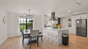 Una cucina moderna con mobili bianchi, un'isola centrale e un frigorifero in acciaio inossidabile.