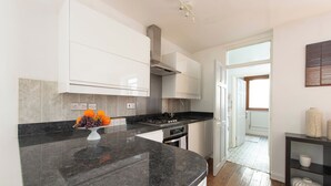 Een moderne keuken met witte kasten, een zwart granieten aanrecht en een fruitschaal.