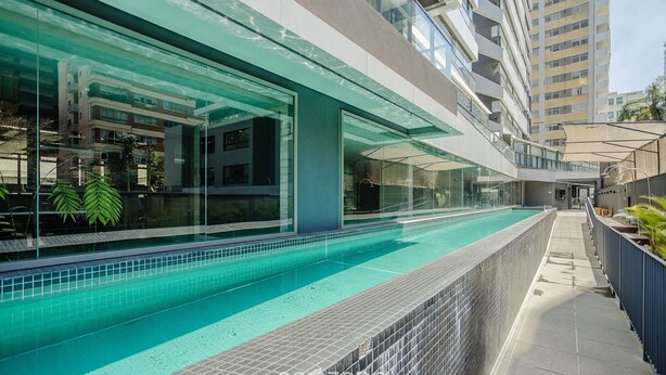 A modern building with a swimming pool, glass walls, and a covered walkway. -  Studio w/ pool near subway FRE2112 (São Paulo)