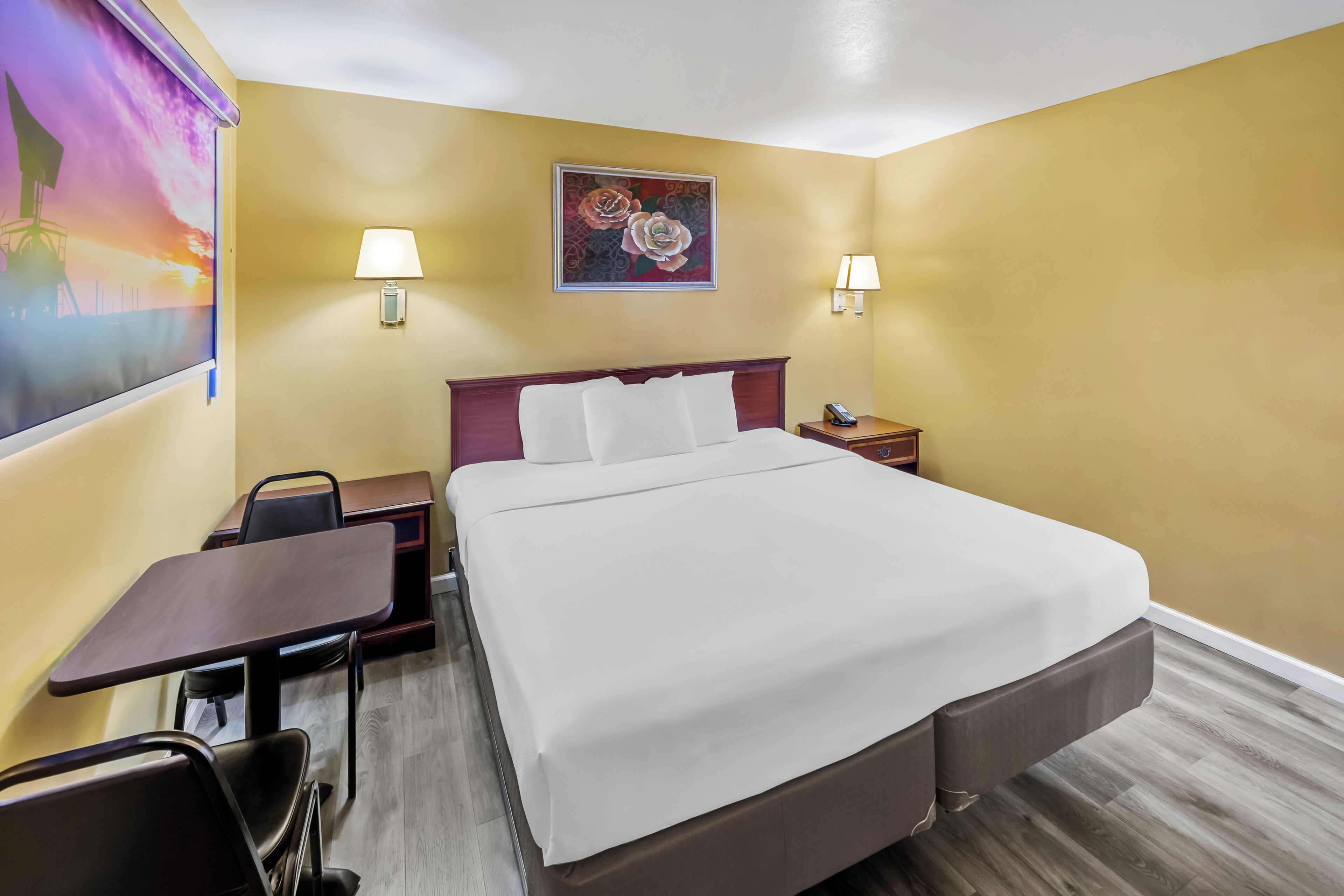 Ein Hotelzimmer mit einem Bett, einem Schreibtisch, Stühlen und zwei Wandlampen.