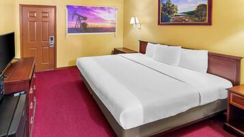Een hotelkamer met een groot bed, een televisie, een bureau en een schilderij aan de muur.