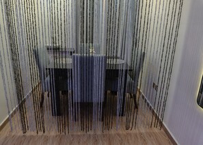 Een eetgedeelte met een glazen tafel en stoelen, omringd door een hek van gaas.