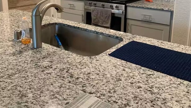 Cozinha com bancadas de granito, eletrodomésticos de aço inoxidável e armários brancos.