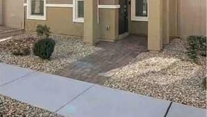 Uma casa de dois andares com entrada frontal, um pequeno alpendre e uma porta visível.