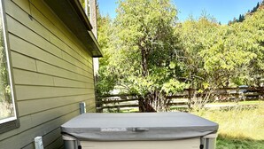 Un bain à remous avec un banc en bois devant, un barbecue et une terrasse couverte.
