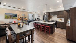 Een moderne keuken met een centraal eiland, een bar met barkrukken en een zithoek met een bank en stoelen.