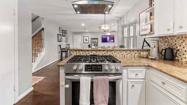 Una cocina moderna con armarios blancos, estufa de acero inoxidable y salpicadero de azulejos.