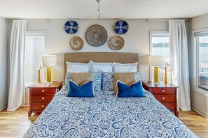 Ein Schlafzimmer mit einem großen Bett, zwei Nachttischen, einem Kopfteil und dekorativen Wandgestaltungen.