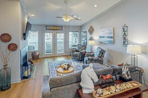 Ein geräumiges Wohnzimmer mit einem großen grauen Sofa, einem Couchtisch mit Dekoration und Blick auf einen Balkon durch Glastüren.