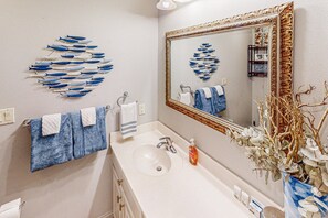 Ein Badezimmer mit Waschbecken, Spiegel und Wandbildern von Fischen.