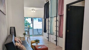 A modern interior with a sofa, ottoman, and a small table with a plant. A staircase leads to an outdoor area with a chair and a table. - Ocean Lovers Taganga Dive Center& Hostel (Taganga)