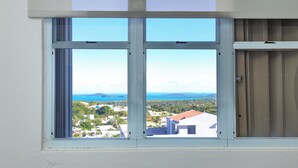 A window with a view of a coastal landscape, including houses and a body of water. - Coastal Retreat Pool Ocean View Fajardo (Fajardo)