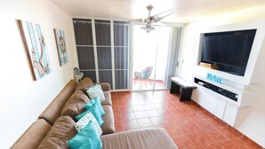 A living room with a sofa, a TV, and artwork on the wall. - Coastal Retreat Pool Ocean View Fajardo (Fajardo)