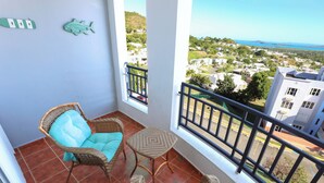 A balcony with wicker furniture and a view of a residential area. - Coastal Retreat Pool Ocean View Fajardo (Fajardo)