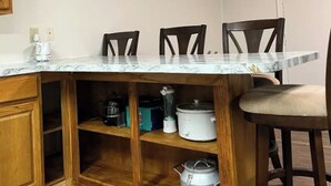 Una cocina con encimera de mármol, armarios de madera y estante empotrado con electrodomésticos.