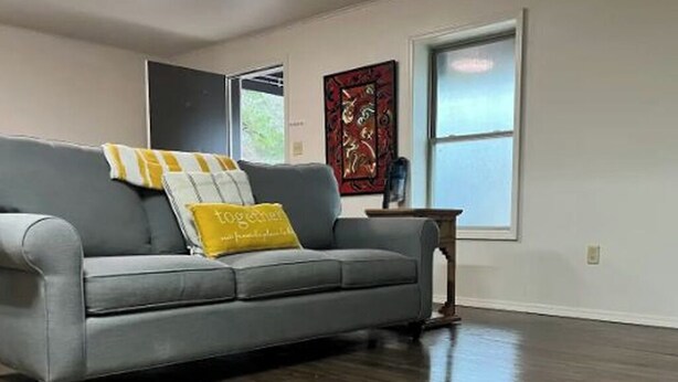 Una sala de estar con un sofá gris, un cojín amarillo y una mesa de centro de madera.