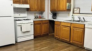 Una cocina con armarios de madera, un refrigerador blanco, una estufa y un fregadero.