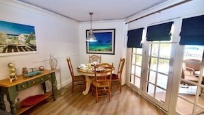 Un coin repas avec une table en bois, quatre chaises, un vase décoratif et un tableau accroché au mur.
