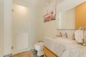 A modern bathroom with a marble sink, a toilet, and a shower. - Penthouse in Puerto Cancún with a Beach and Dock on the Property. | Sleeps 10. (Puerto Cancun)