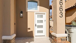 A residential entrance with a white door, a stone pillar with the number 1663, and a small window above the door.