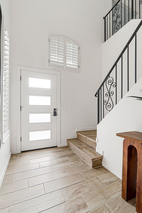 A staircase with a wooden handrail and a metal railing with a decorative design.