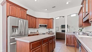 A modern kitchen with wooden cabinets, stainless steel appliances, and a large island. - Aqua Dream Home for 11 (St. Augustine)