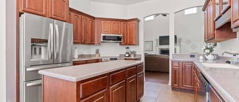 A modern kitchen with wooden cabinets, stainless steel appliances, and a large island.