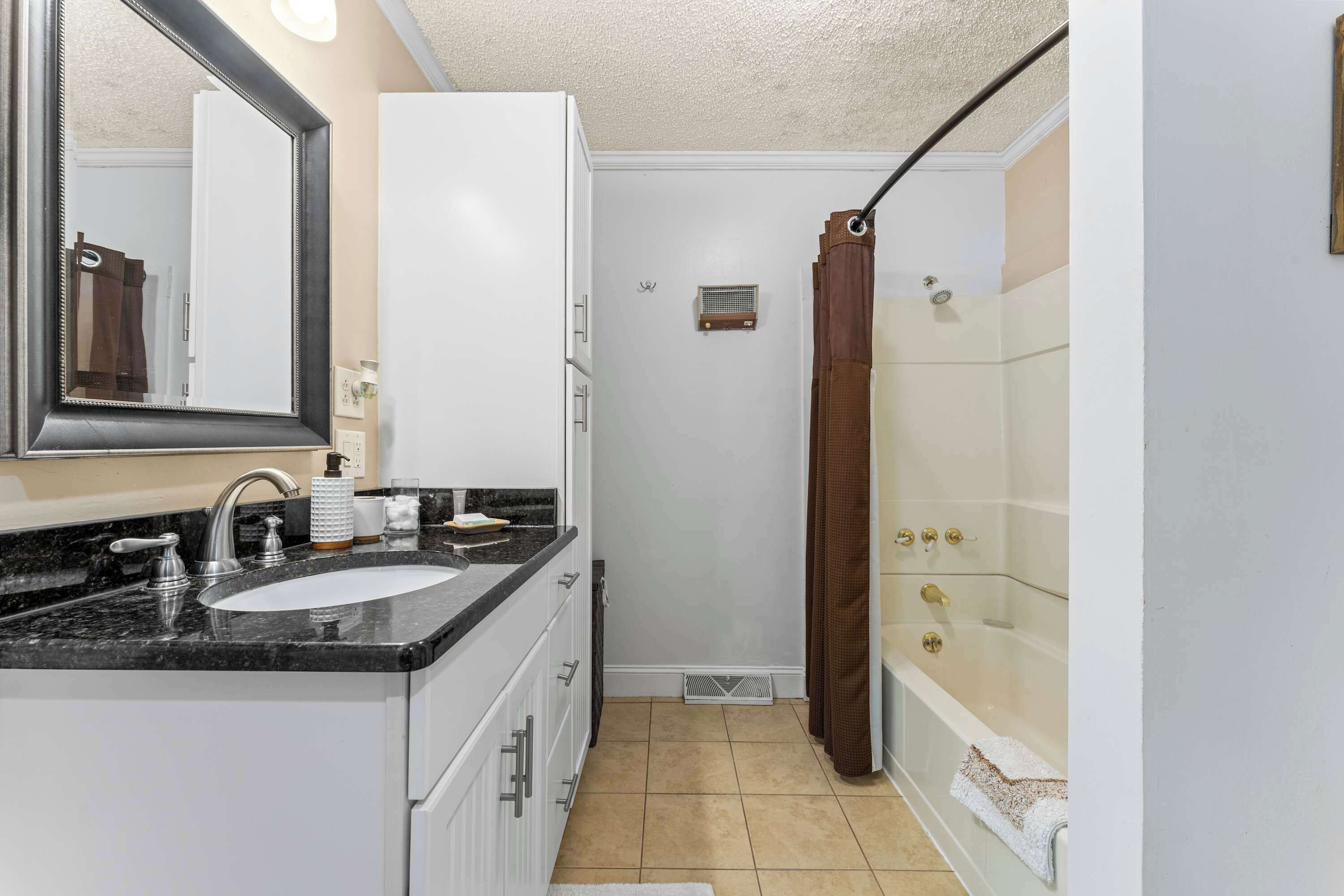 A bathroom with a sink, mirror, shower, and bathtub.