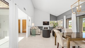 Ein modernes Wohnzimmer mit einem Glastisch, Sofas und einem Fernseher.