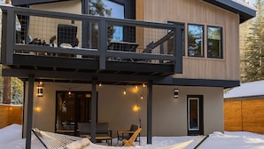 Une maison moderne à deux étages, dotée d’un balcon, d’un hamac et de guirlandes lumineuses.