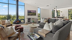 Una sala de estar moderna con chimenea, ventanas amplias y vistas al exterior.