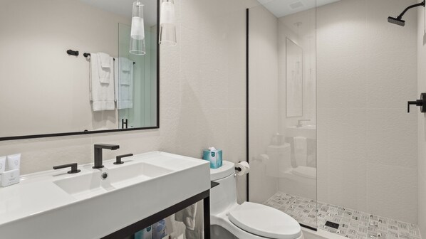 Un baño moderno con tocador de doble lavabo, inodoro y zona de ducha.