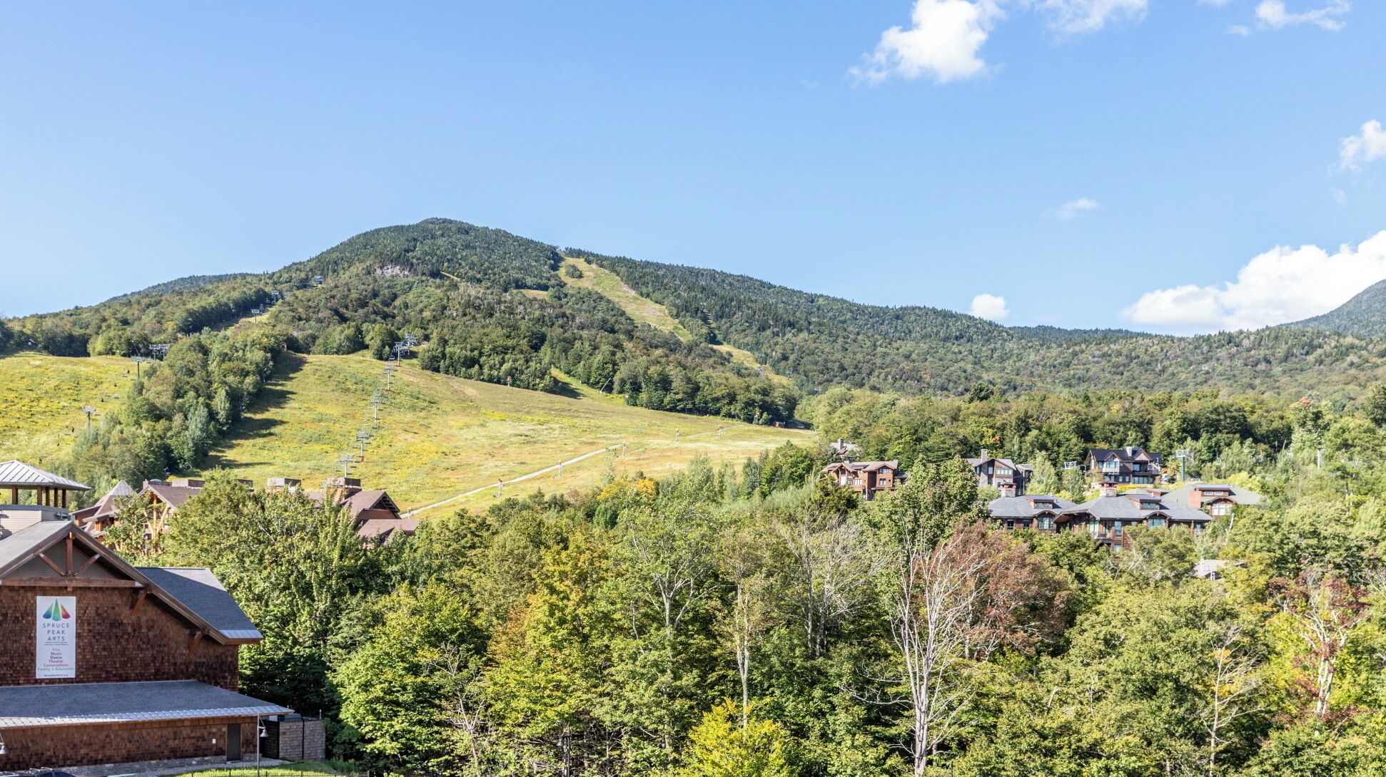 A mountain village with traditional wooden houses, a ski lift, and a building labeled "Spruce Peak."