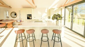 Una cucina moderna con una grande isola, sgabelli da bar e vista attraverso una porta in vetro.