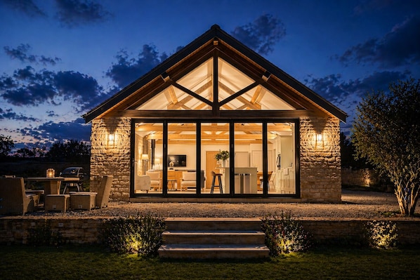 A stone house with a large glass front, wooden beams, and a stone exterior.