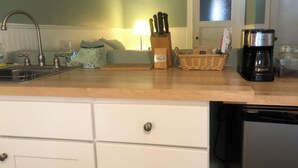 A kitchen with a sink, a coffee maker, a basket, and a door with a window. - Jersey Street Gem: Charming 1 Bedroom 1Bathroom (San Francisco)