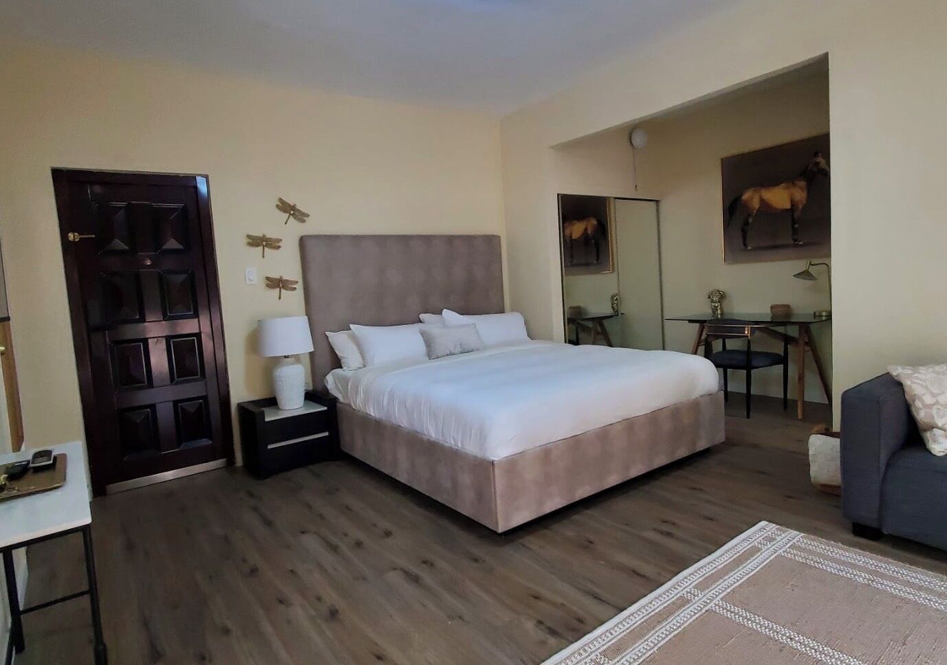 A bedroom with a bed, a desk, a chair, a dresser, and a door.