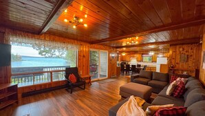 L’intérieur d’un chalet accueillant, avec un plancher en bois, un canapé, un coin repas et une vue sur un lac.