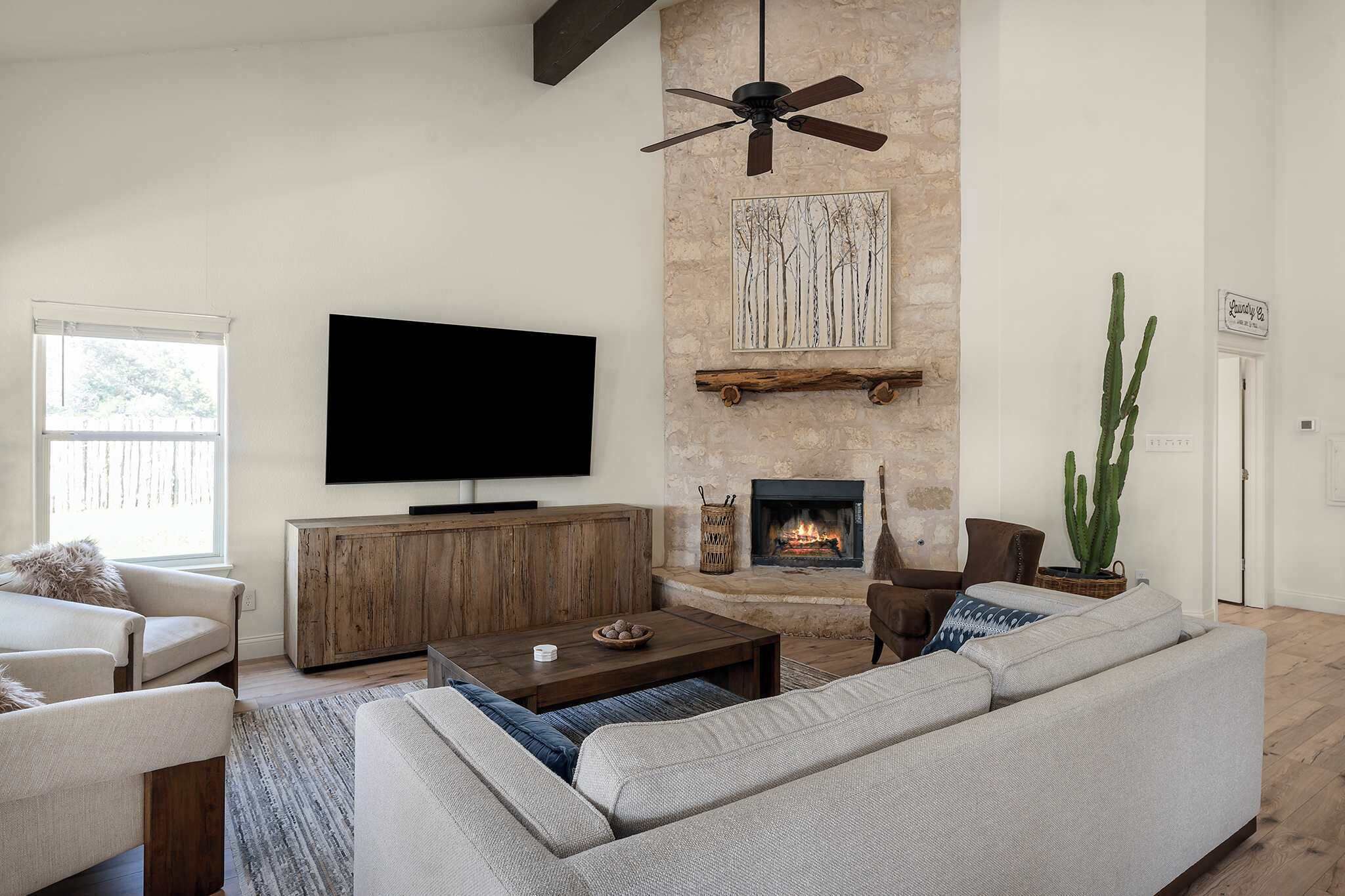 A living room with a fireplace, a television, and a ceiling fan.