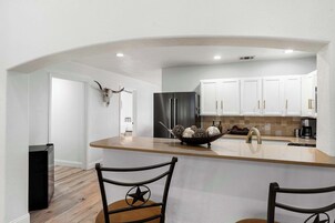 Una cocina moderna con armarios blancos, un refrigerador negro y una isla central con un cuenco de objetos decorativos.