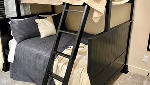 A bunk bed with a ladder, a desk, and a chair.
