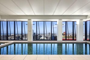 A modern indoor pool with large windows offering city views.