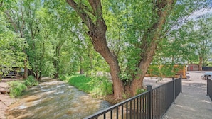 Ein Fluss fließt durch einen Park mit Bäumen und einer Holzbrücke.