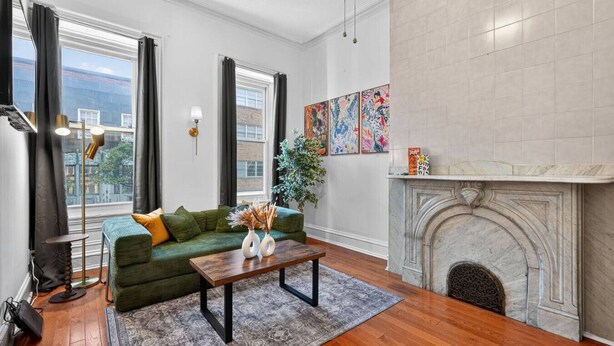 A living room with a green sofa, a wooden coffee table, a fireplace, and artwork on the wall.