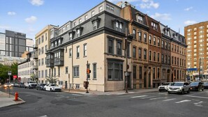 A multi-story building with a corner intersection, featuring a mix of architectural styles and parked cars along the street.